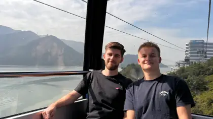 My brother and me in a cable car above water and green hills