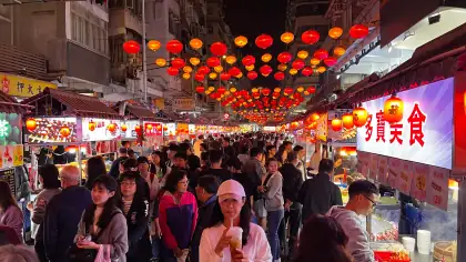 A busy night market with rows of red lanterns overhead
